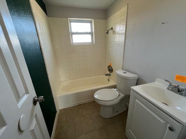 full bathroom featuring tile patterned floors, vanity, tiled shower / bath combo, and toilet