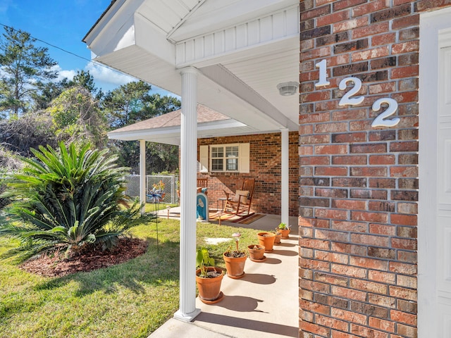 entrance to property with covered porch and a yard