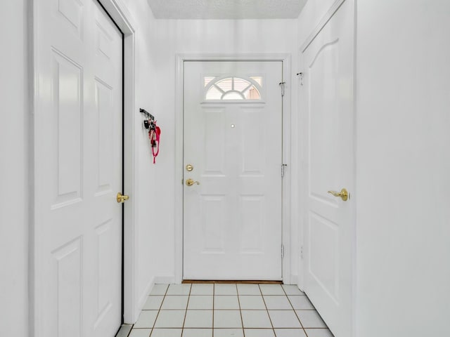 doorway with light tile patterned floors and a textured ceiling