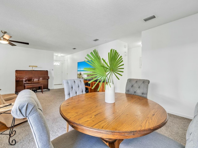 dining space with ceiling fan, a textured ceiling, and light carpet