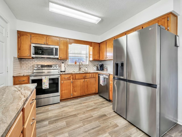 kitchen with light stone countertops, tasteful backsplash, a textured ceiling, stainless steel appliances, and sink