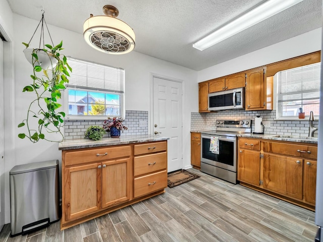 kitchen featuring decorative backsplash, stainless steel appliances, plenty of natural light, and sink