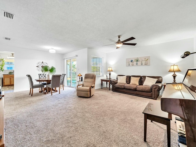 carpeted living room with ceiling fan and a textured ceiling