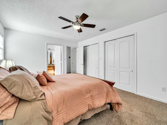 carpeted bedroom with two closets, ceiling fan, and a textured ceiling