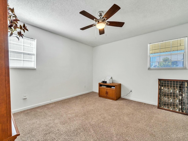 carpeted spare room featuring a textured ceiling and ceiling fan