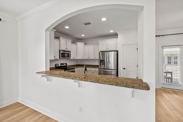 258 Tropical Breeze Dr, Santa Rosa Beach, FL 32459 - kitchen with stainless steel appliances, a breakfast bar, light wood-type flooring, a peninsula, and arched walkways