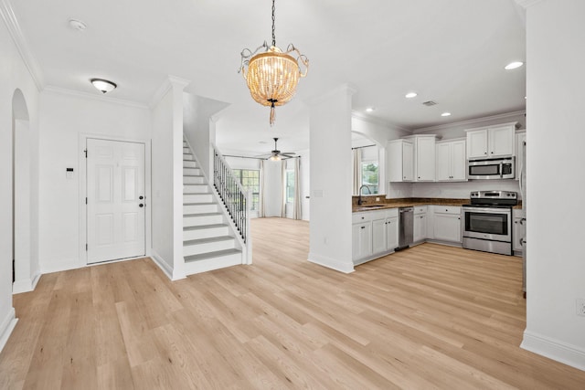 258 Tropical Breeze Dr, Santa Rosa Beach, FL 32459 - kitchen with appliances with stainless steel finishes, ornamental molding, light wood-style flooring, open floor plan, and white cabinetry
