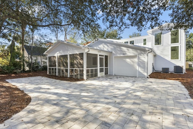 rear view of house featuring central AC, a sunroom, and a garage