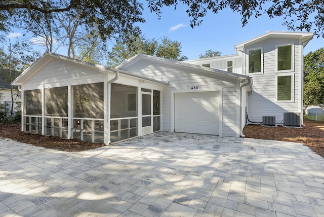 rear view of property with a garage, cooling unit, and a sunroom