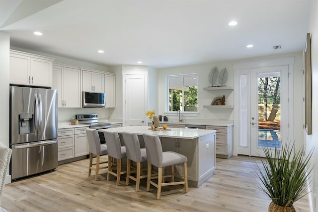 kitchen with stainless steel appliances, a kitchen island, white cabinets, and plenty of natural light