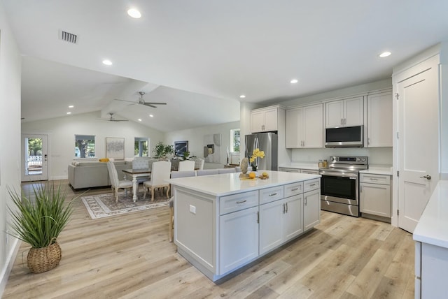 kitchen featuring white cabinets, lofted ceiling, light wood-type flooring, a kitchen island, and appliances with stainless steel finishes