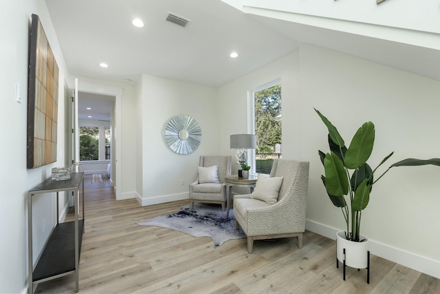 sitting room with light wood-type flooring, vaulted ceiling, and plenty of natural light