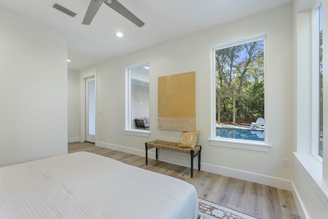 bedroom with ceiling fan, light hardwood / wood-style flooring, and multiple windows