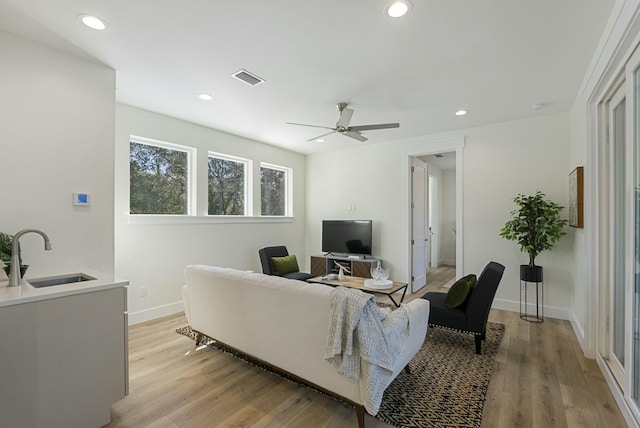 living room featuring sink, ceiling fan, and light hardwood / wood-style flooring