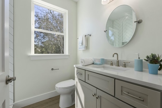 bathroom featuring toilet, hardwood / wood-style flooring, a healthy amount of sunlight, and vanity