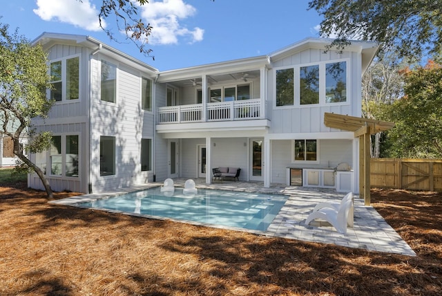 rear view of property with a balcony, a pergola, ceiling fan, a patio, and a fenced in pool