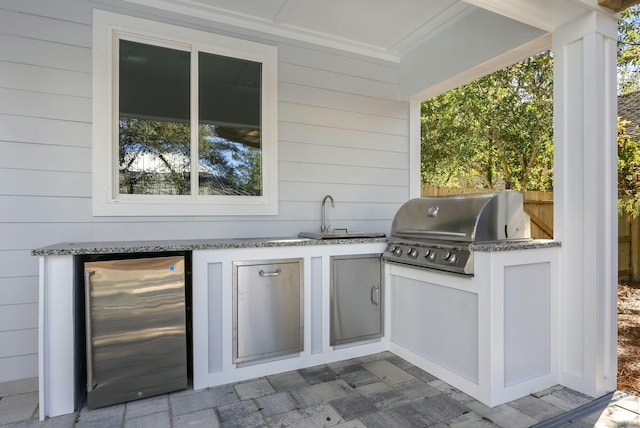 view of patio with area for grilling, an outdoor kitchen, sink, and wine cooler