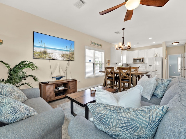 living room featuring ceiling fan with notable chandelier and light hardwood / wood-style flooring