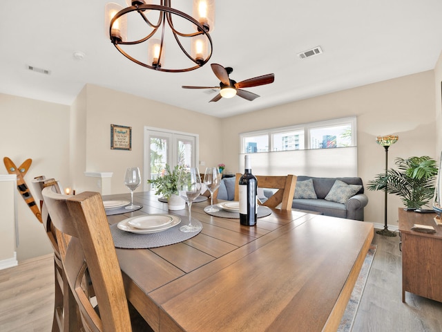 dining space featuring ceiling fan with notable chandelier, light wood-type flooring, and french doors