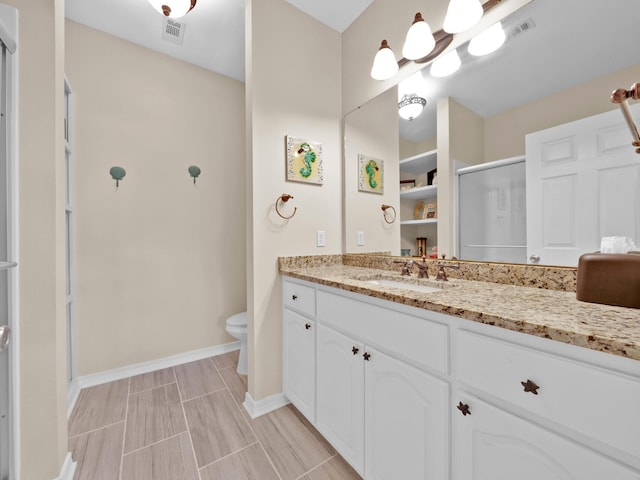 bathroom featuring vanity, toilet, and an enclosed shower