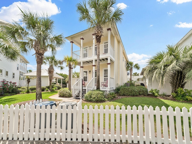 view of front of house featuring a balcony, a front lawn, and covered porch