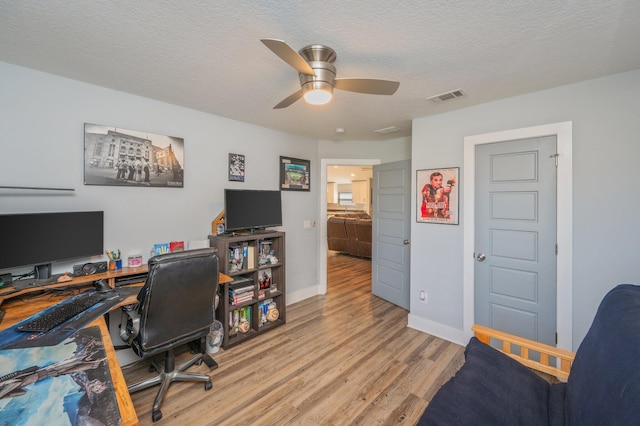 office space with ceiling fan, a textured ceiling, and light wood-type flooring