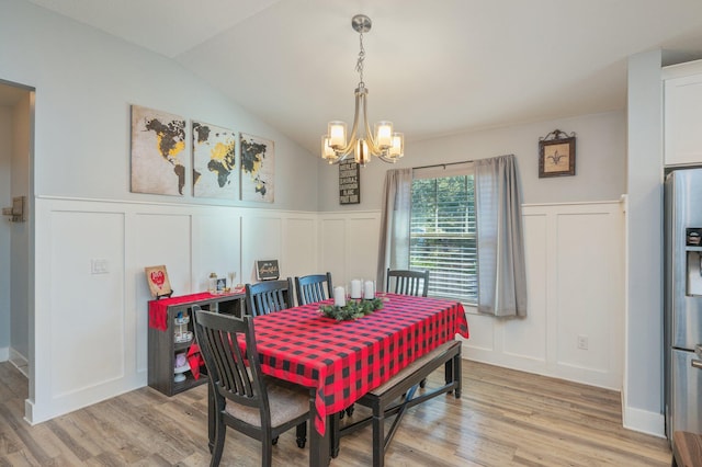 dining area featuring light wood-type flooring, an inviting chandelier, and lofted ceiling