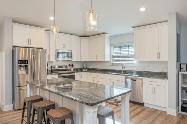 kitchen featuring white cabinetry, sink, a kitchen breakfast bar, a kitchen island, and appliances with stainless steel finishes