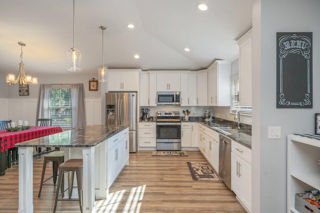 kitchen with white cabinets, sink, stainless steel appliances, and a breakfast bar area