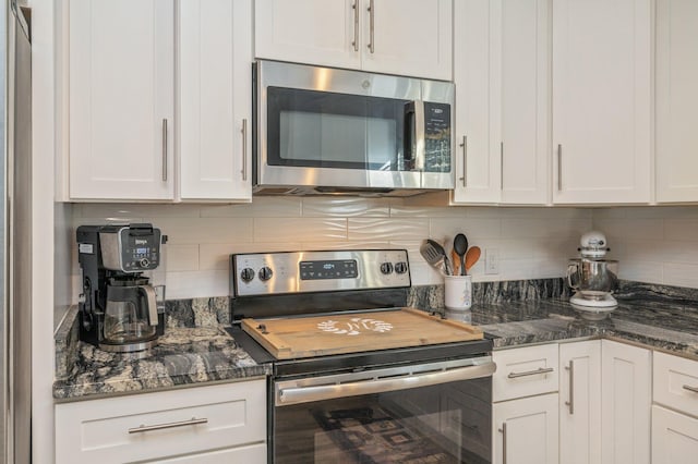 kitchen featuring tasteful backsplash, white cabinetry, appliances with stainless steel finishes, and dark stone counters