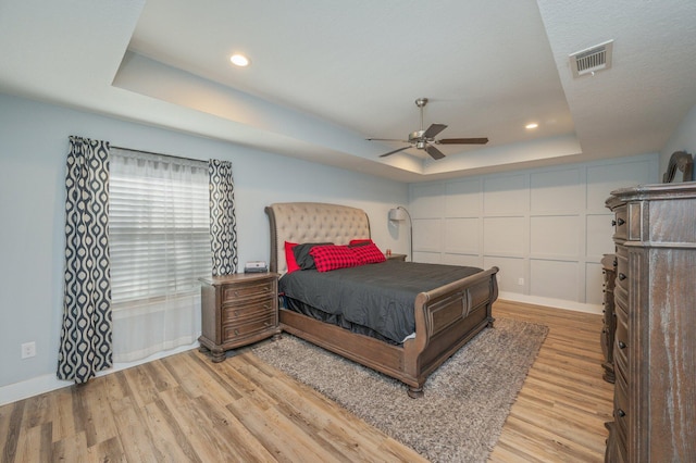 bedroom featuring a tray ceiling, light hardwood / wood-style flooring, and ceiling fan