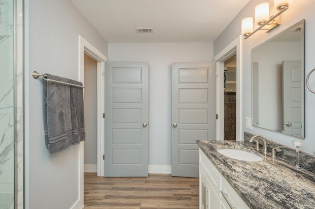 bathroom with hardwood / wood-style flooring, vanity, and a textured ceiling