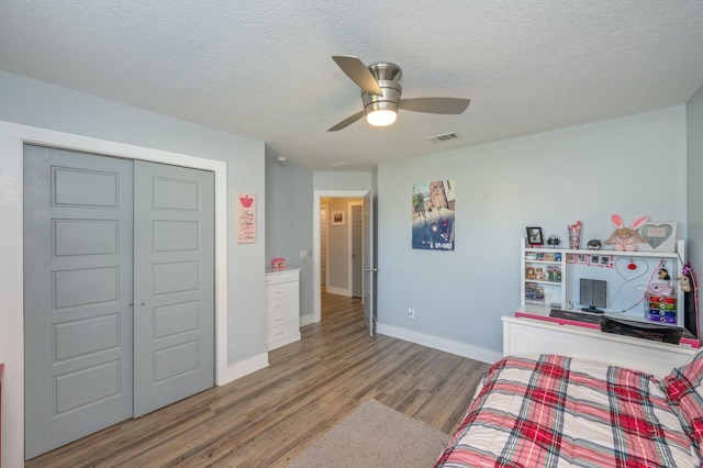 bedroom with hardwood / wood-style floors, ceiling fan, a textured ceiling, and a closet