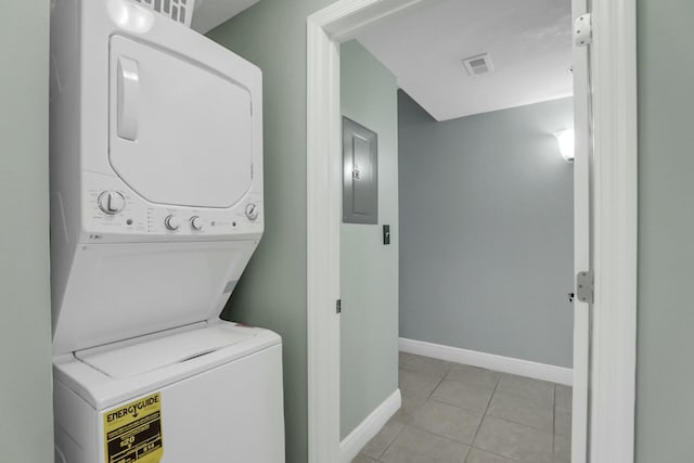 laundry area with electric panel, light tile patterned floors, and stacked washer and clothes dryer