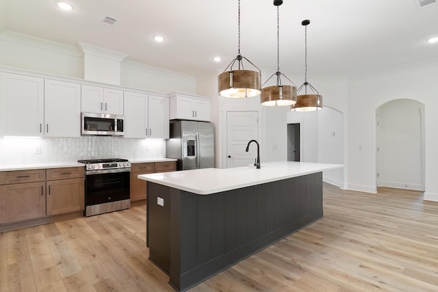 kitchen with tasteful backsplash, visible vents, arched walkways, appliances with stainless steel finishes, and ornamental molding