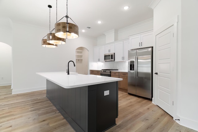 kitchen with arched walkways, appliances with stainless steel finishes, crown molding, light wood-type flooring, and recessed lighting