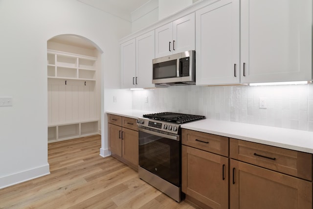 kitchen featuring decorative backsplash, light wood-style flooring, stainless steel appliances, light countertops, and white cabinetry