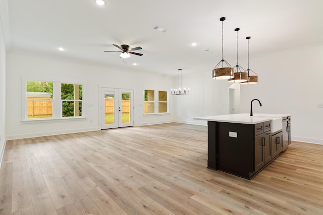 kitchen featuring open floor plan, light countertops, a sink, and light wood-style floors