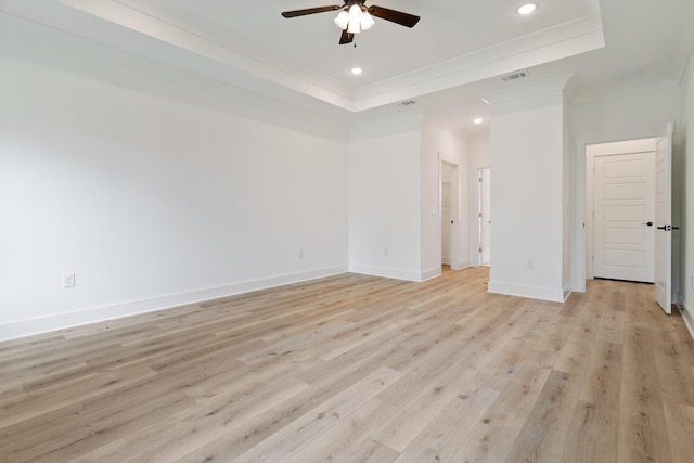 empty room featuring ornamental molding, a raised ceiling, visible vents, and light wood finished floors