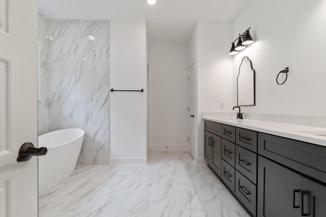 bathroom with double vanity, marble finish floor, a freestanding tub, and a sink