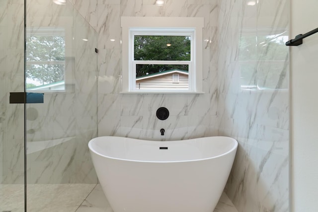 bathroom featuring marble finish floor, a walk in shower, and a freestanding bath