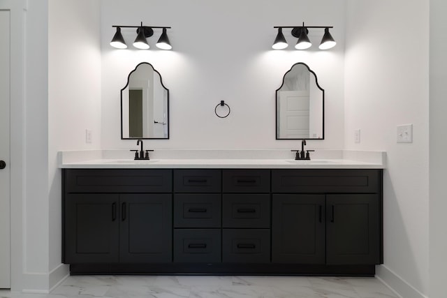 full bath with marble finish floor, a sink, baseboards, and double vanity