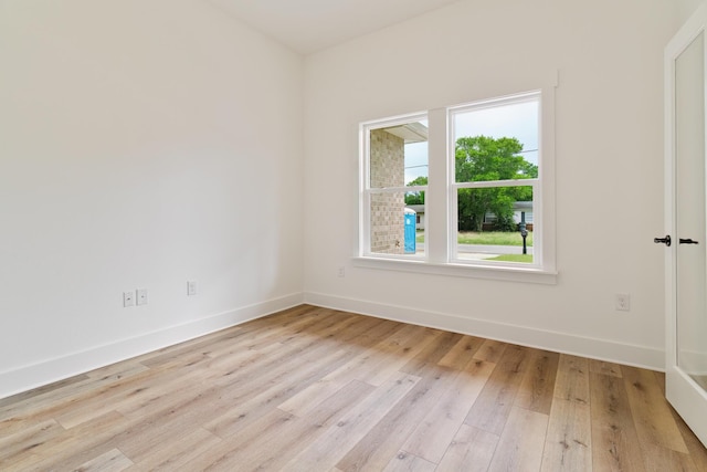 empty room featuring light wood finished floors and baseboards