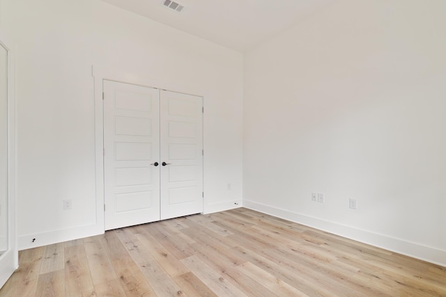 empty room with visible vents, light wood-style flooring, and baseboards