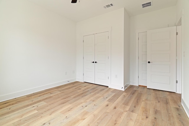 unfurnished bedroom featuring light wood-style flooring, a closet, visible vents, and baseboards