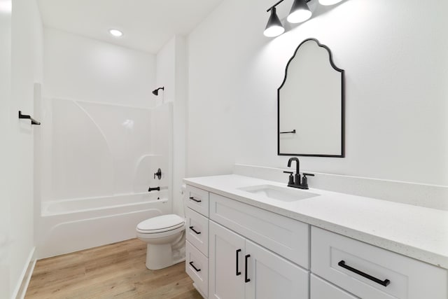 bathroom with toilet, recessed lighting, wood finished floors, vanity, and  shower combination