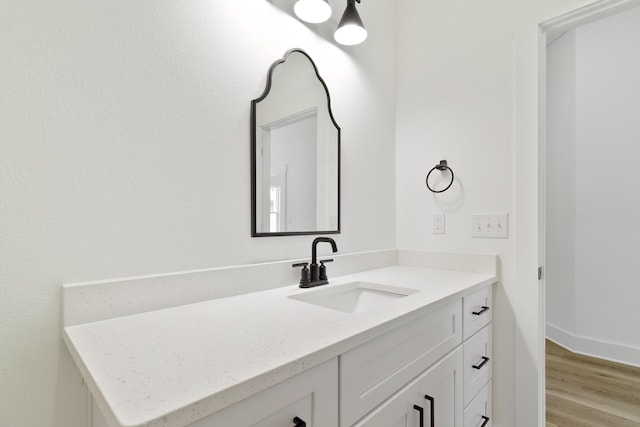 bathroom with baseboards, wood finished floors, and vanity