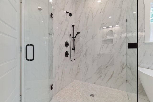 full bathroom featuring a freestanding tub and a marble finish shower