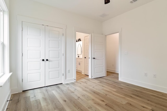 unfurnished bedroom featuring light wood-style floors, a closet, visible vents, and baseboards