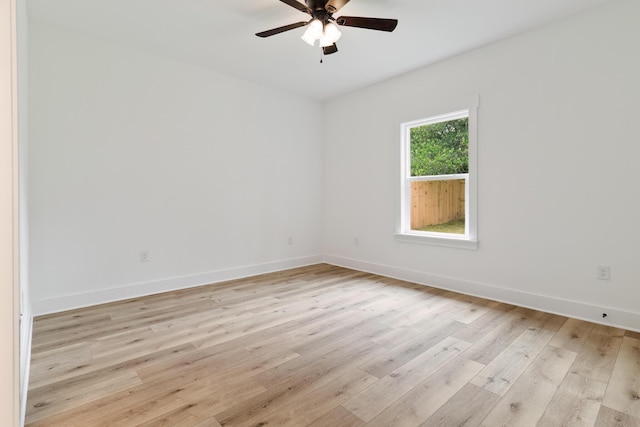 spare room with light wood-type flooring, a ceiling fan, and baseboards